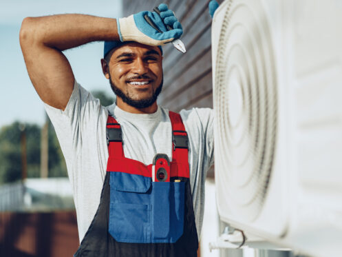 Young black man repairman checking an outside air conditioner unit